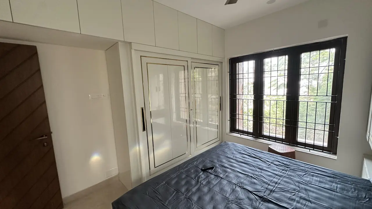 Guest bedroom with white lacquer wardrobes and loft cabinets