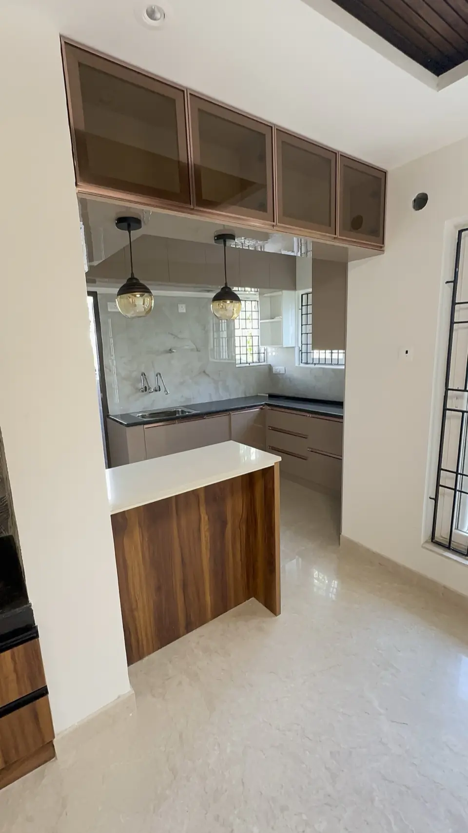 Modular kitchen with glass wall cabinets, pendant lights and quartz counter
